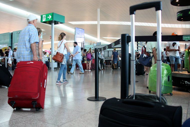 Pla general de viatgers caminant per la T1 de l'aeroport del Prat