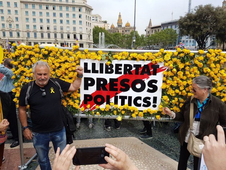 Un home davant d'una tanca amb roses grogues a la plaça de Catalunya