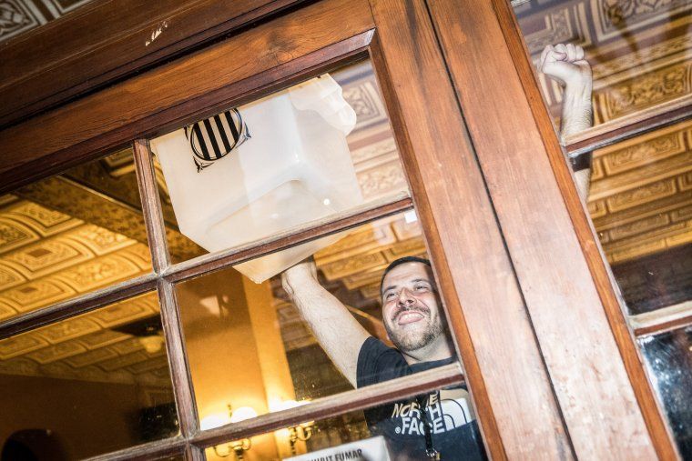 Un noi ensenya una urna que es troba dins d'un col·legi electoral