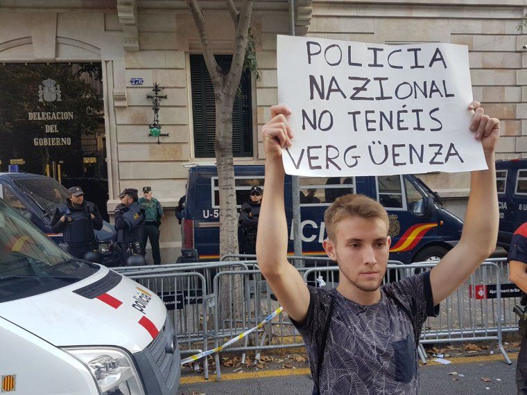 Un noi sosté un cartell contra la policia espanyola davant de la delegació del govern espanyol a Catalunya