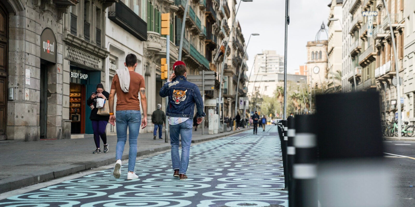 Dos homes caminant pel carrer Pelai, amb un nou espai per a vianants pintat amb panots blaus / ACN