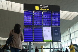 Una passatgera consultant la pantalla de les sortides a la T1 de l'aeroport de Barcelona | ACN