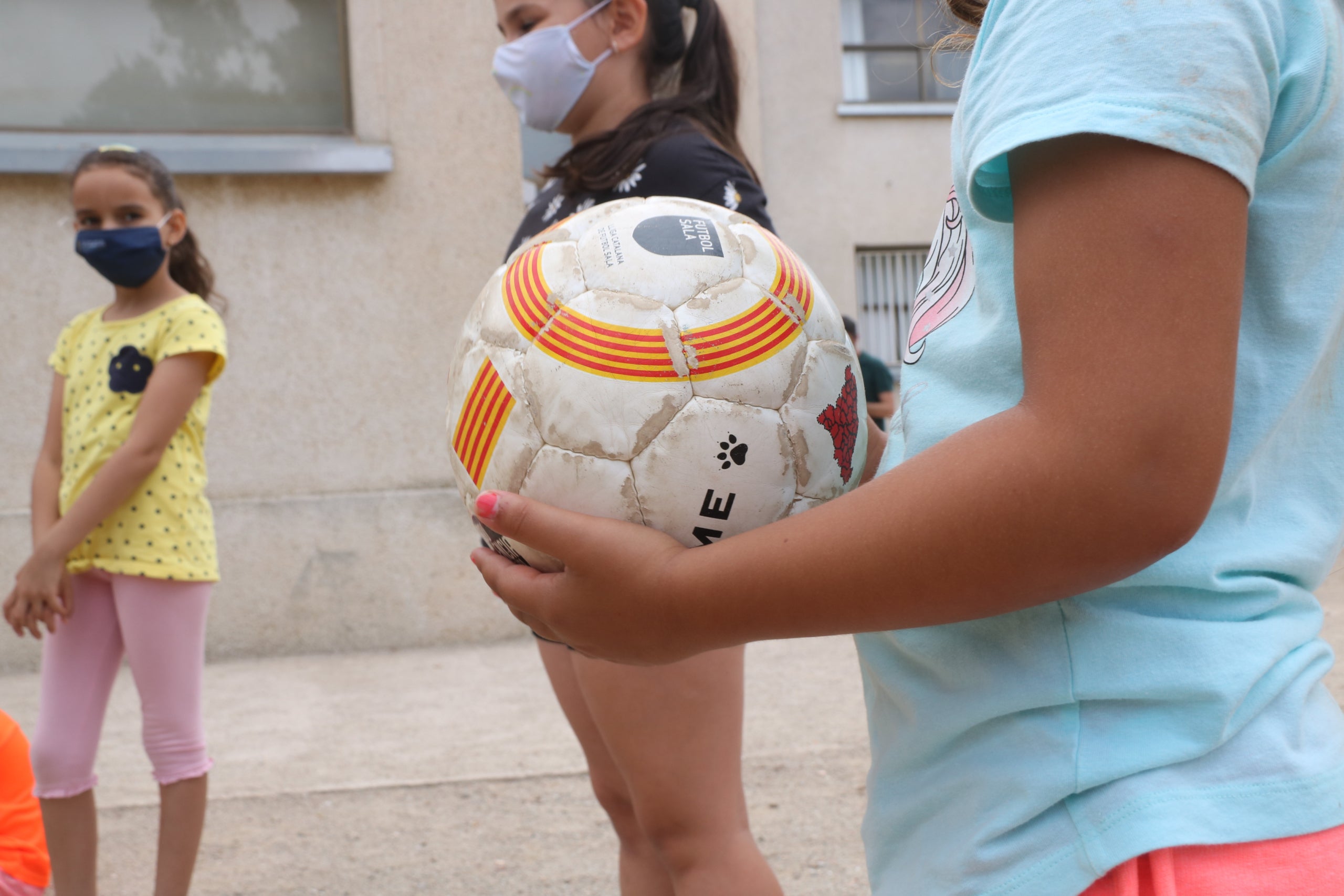 Una pelota a manos de una niña participando al casal de verano de la Fundación Pere Tarrés / ACN