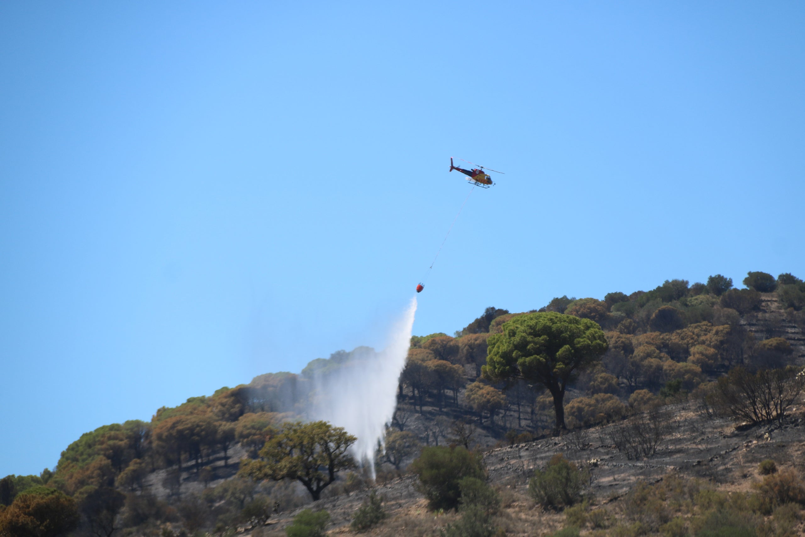 Un helicòpter descarregant en un dels focus de l'incendi de Portbou /ACN