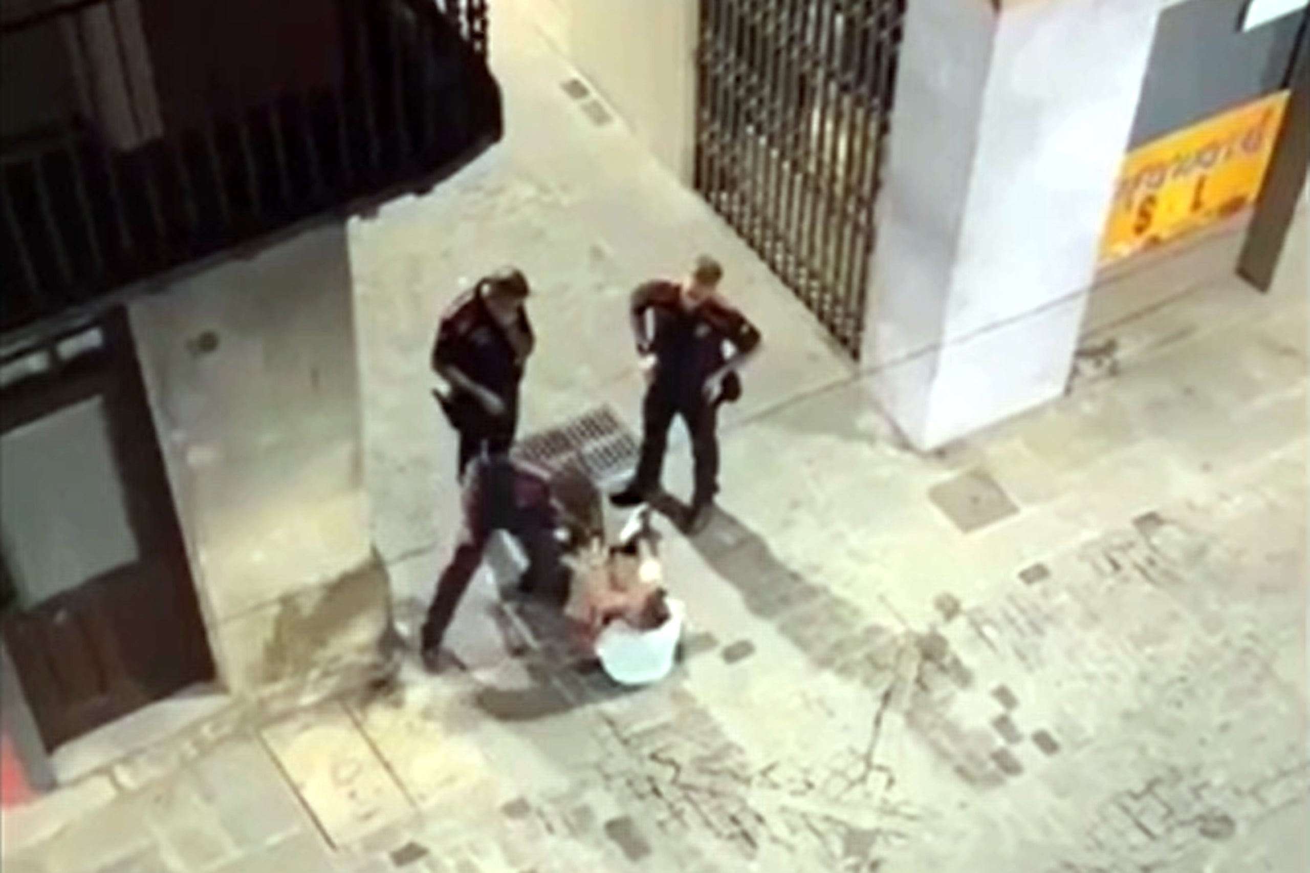 Captura del vídeo del moment en què l'agent dels mossos venta una bufetada a l'home assegut al mig del carrer a Olot / ACN