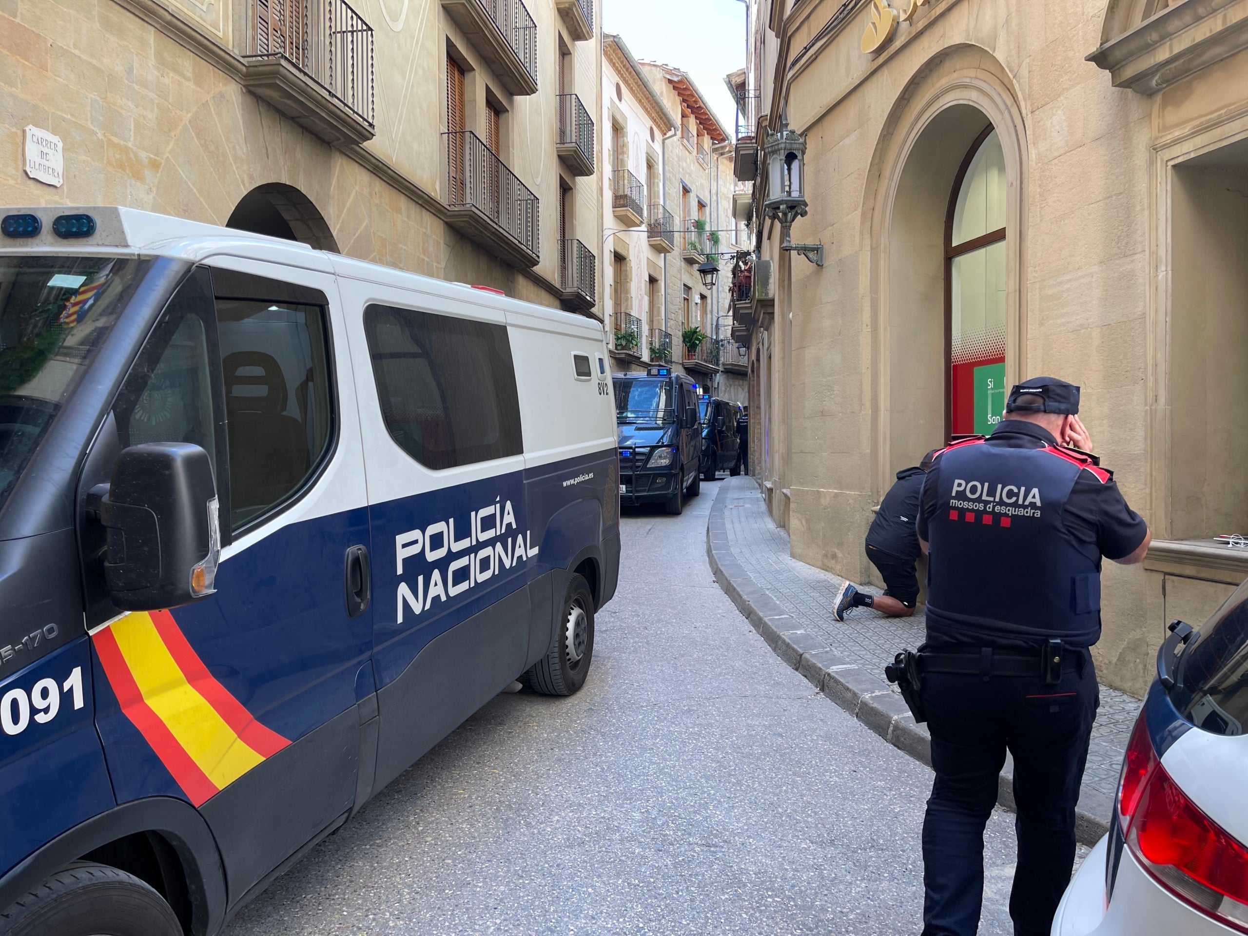 Uno de los Mossos del dispositivo de Solsona conversa por teléfono ante las furgonetas del CNP/Quico Sallés