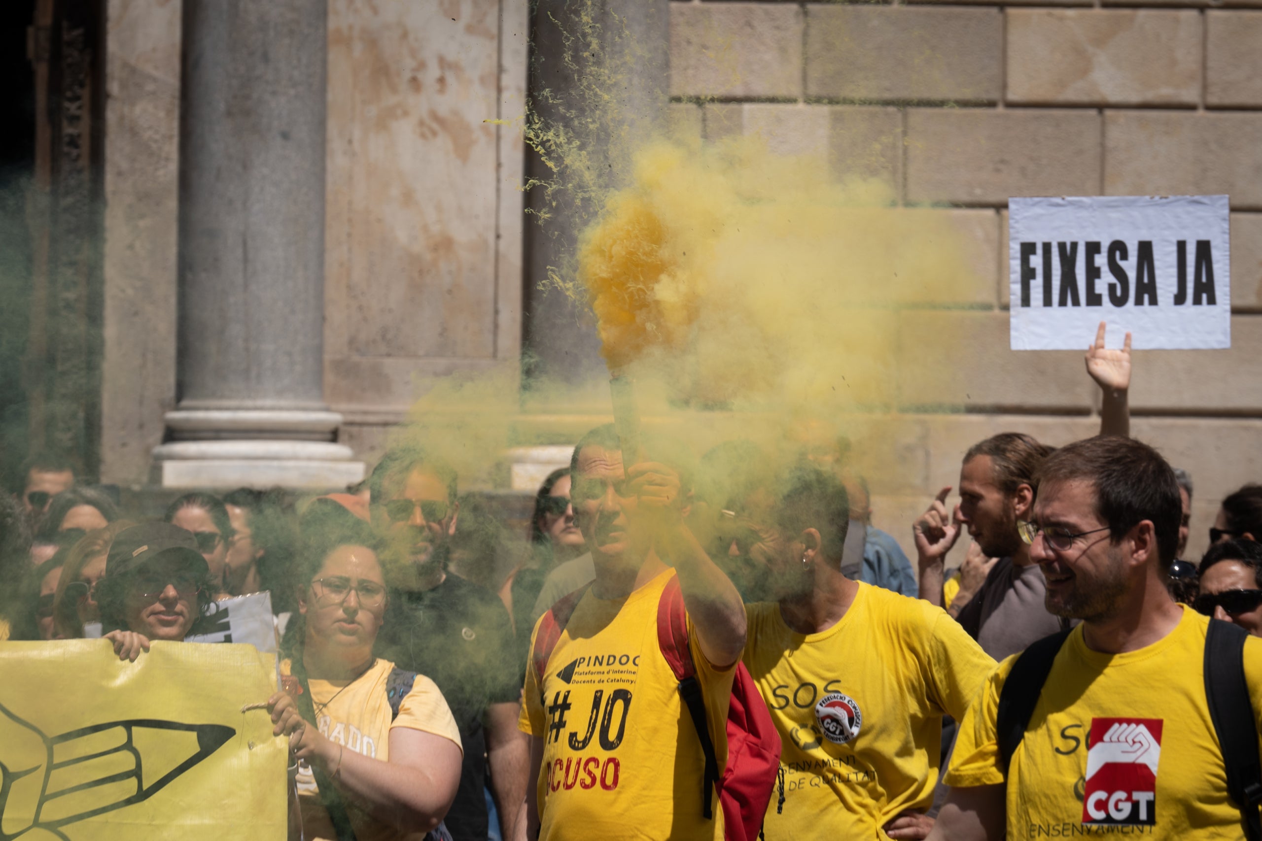 Un home subjecta una bengala groga durant una manifestació enfront del Palau de la Generalitat durant una manifestació d'interins / David Zorrakino (Europa Press)