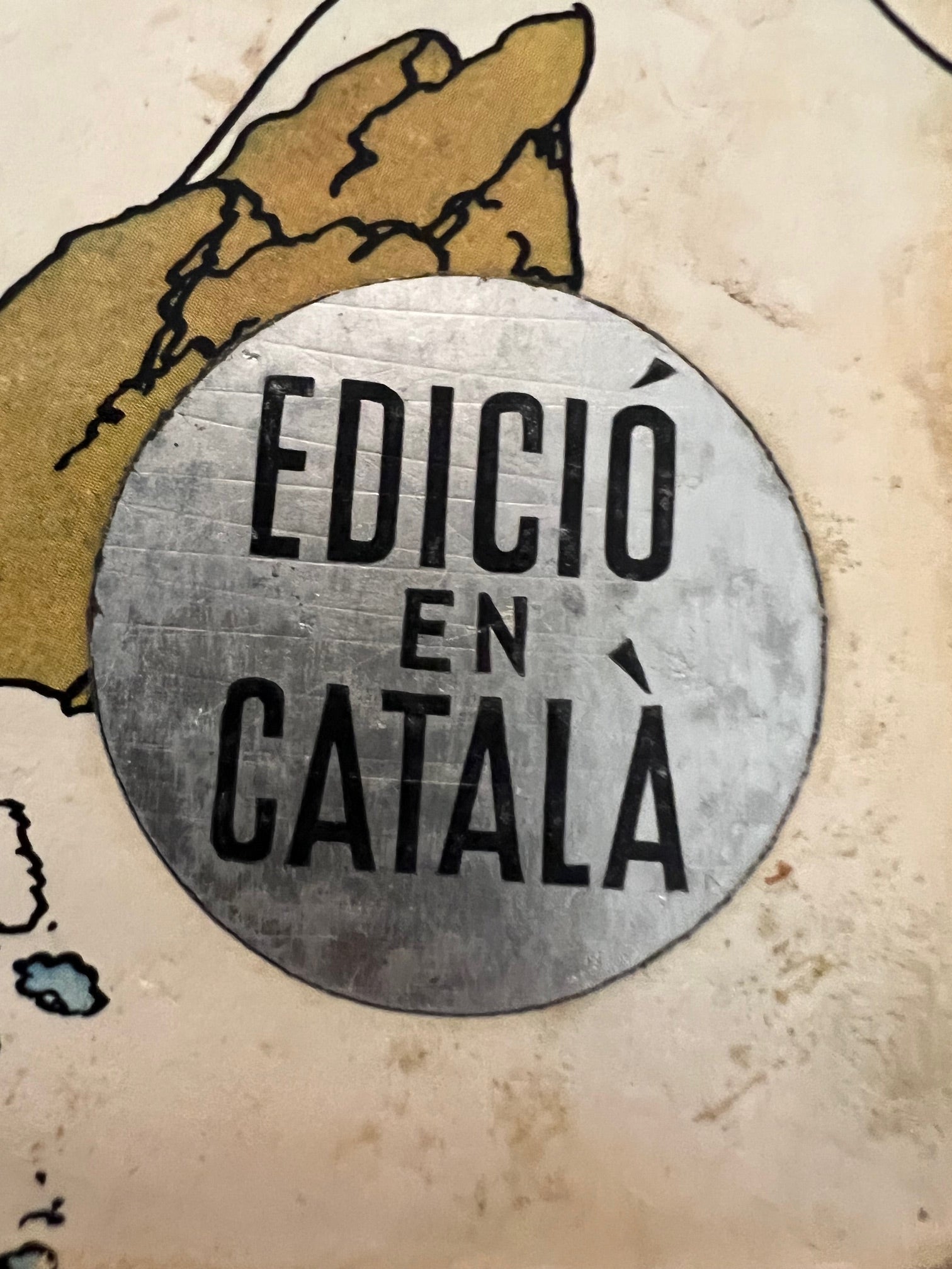 Adhesiu platejat que caracteritzava les edicions en català de les aventures de Tintín.