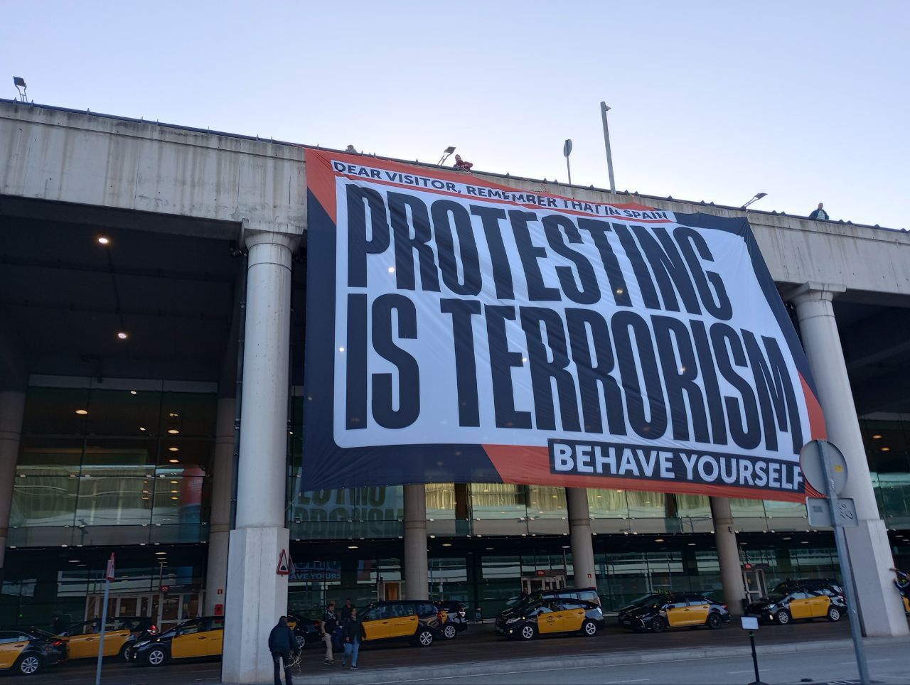La pancarta d'Òmnium Cultural a l'aeroport del Prat per denunciar la causa de Tsunami Democràtic / Òmnium