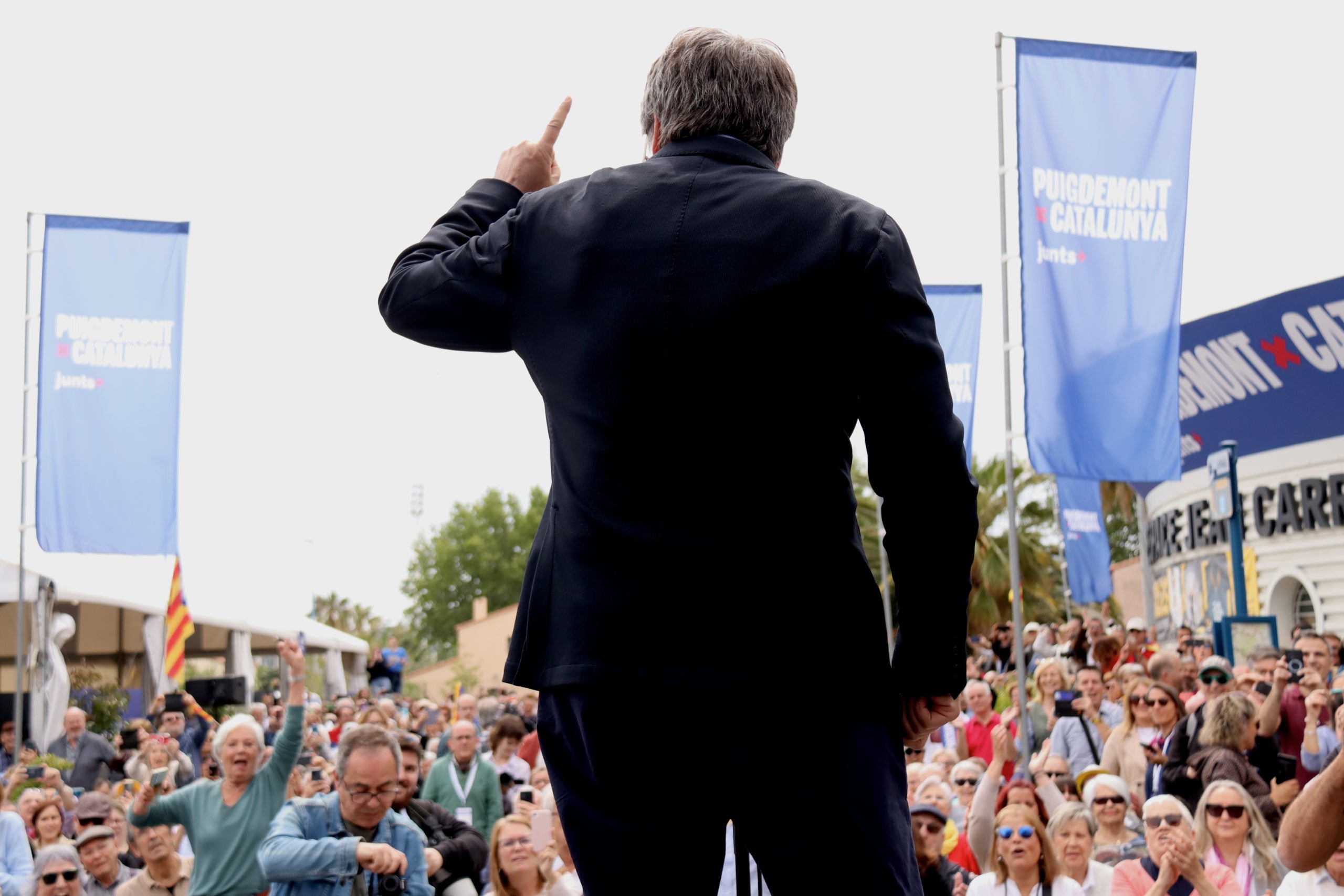 El candidat de Junts+, Carles Puigdemont, saluda el públic que segueix l'acte central de campanya d'Argelers en una pantalla a l'exterior / Nico Tomás I ACN