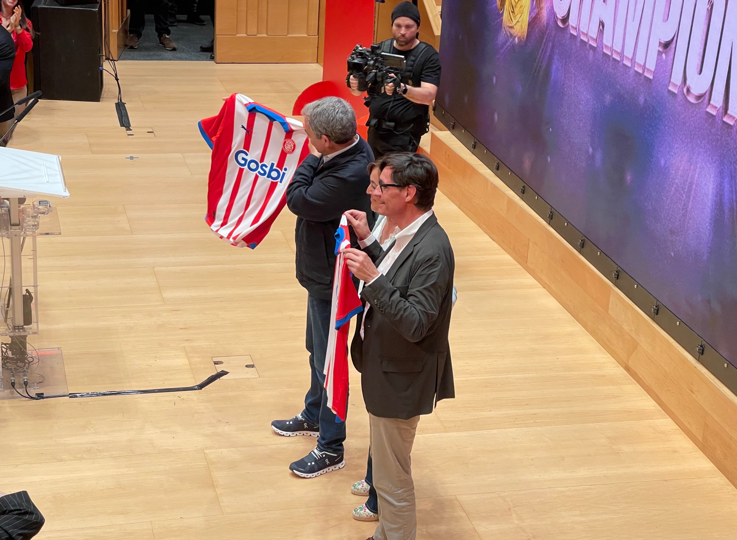 La candidata por Girona, Sílvia Paneke, regala la camiseta del Girona a José Luis Rodríguez i Salvador Illa/QS
