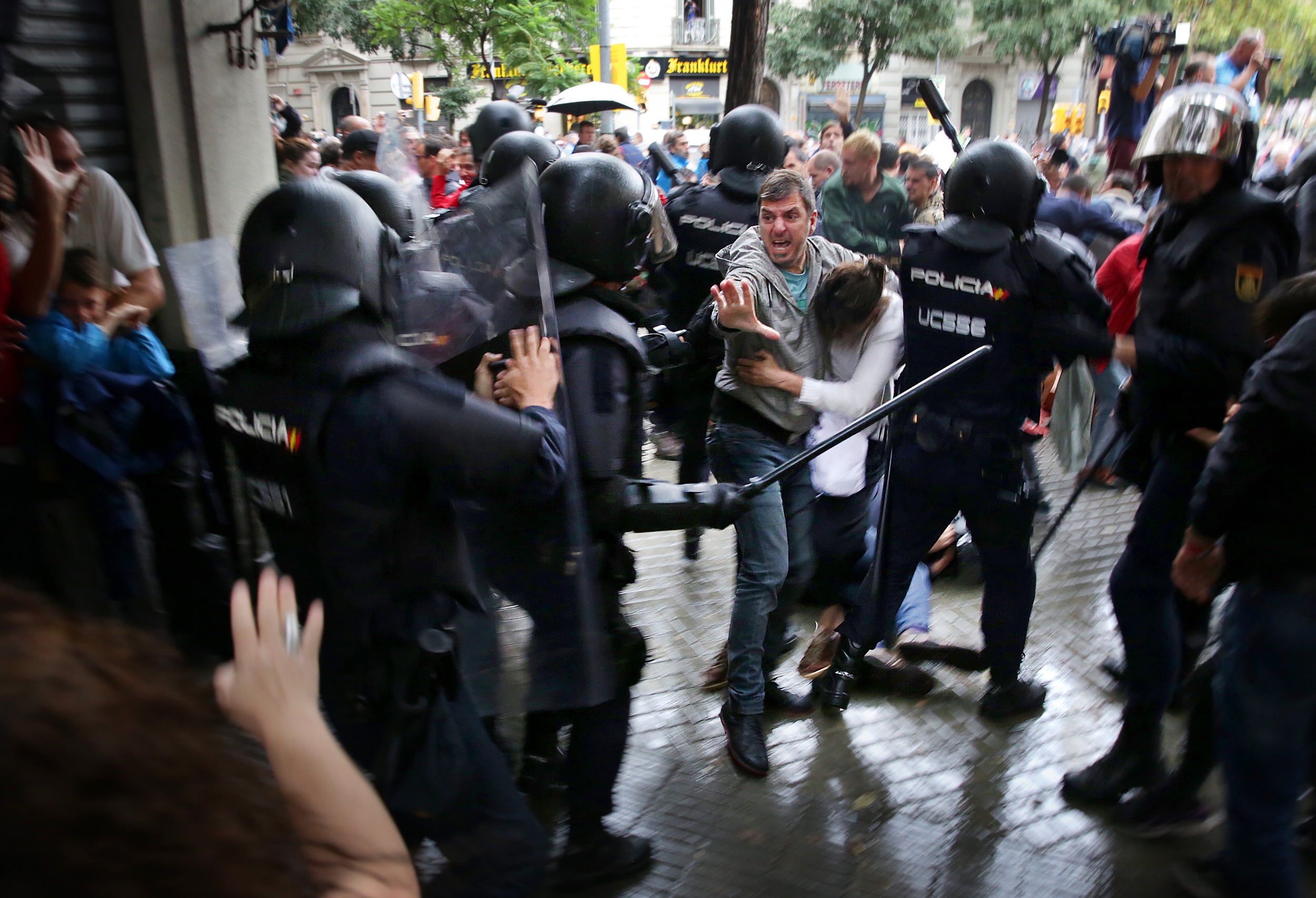 Un home intenta protegir una dona dels cops de porra d'agents antidisturbis de la policia espanyola l'1 d'octubre del 2017 / ACN