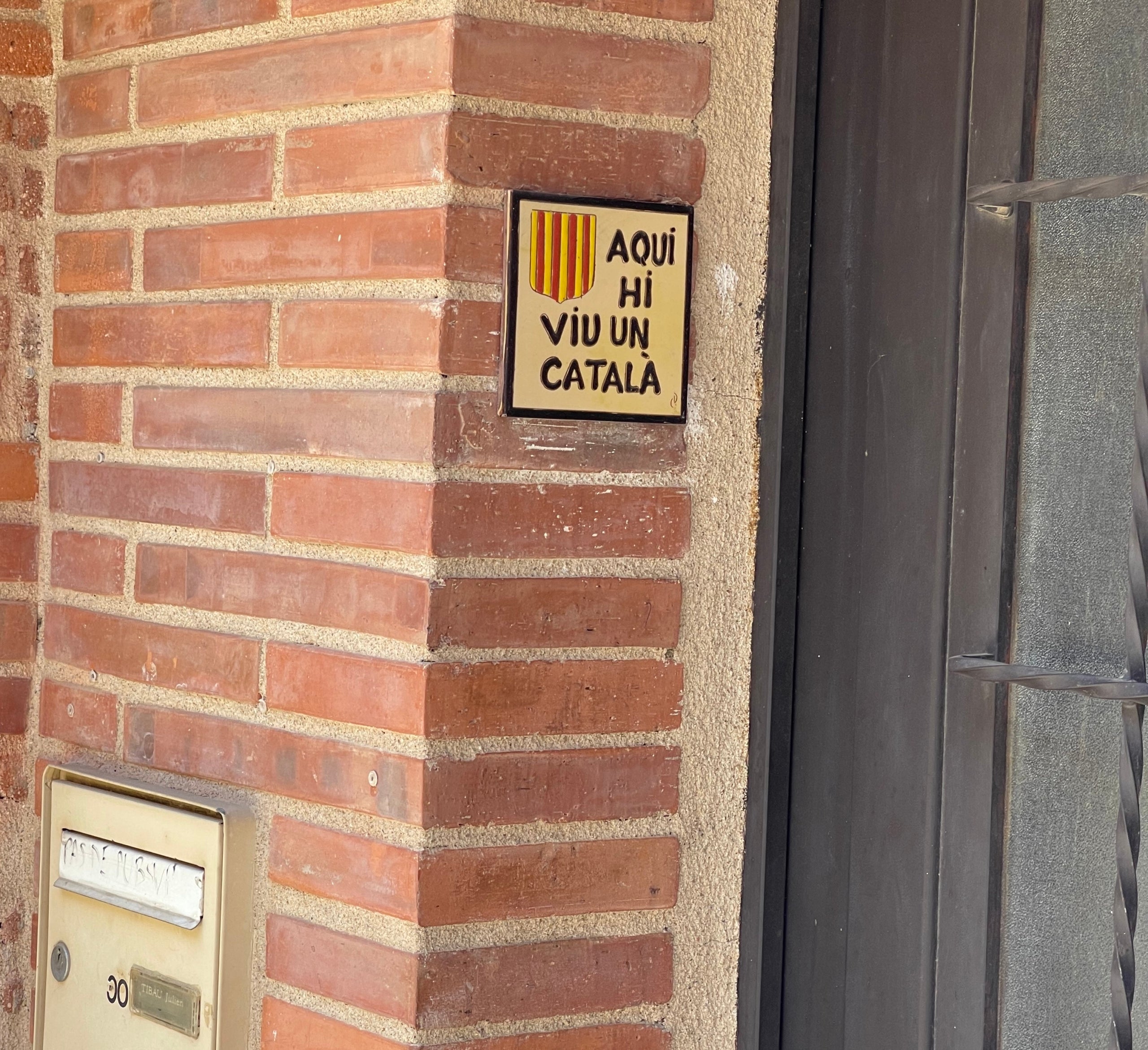 Una rajola en un portal que identifica un irreductible nord-català/Quico Sallés