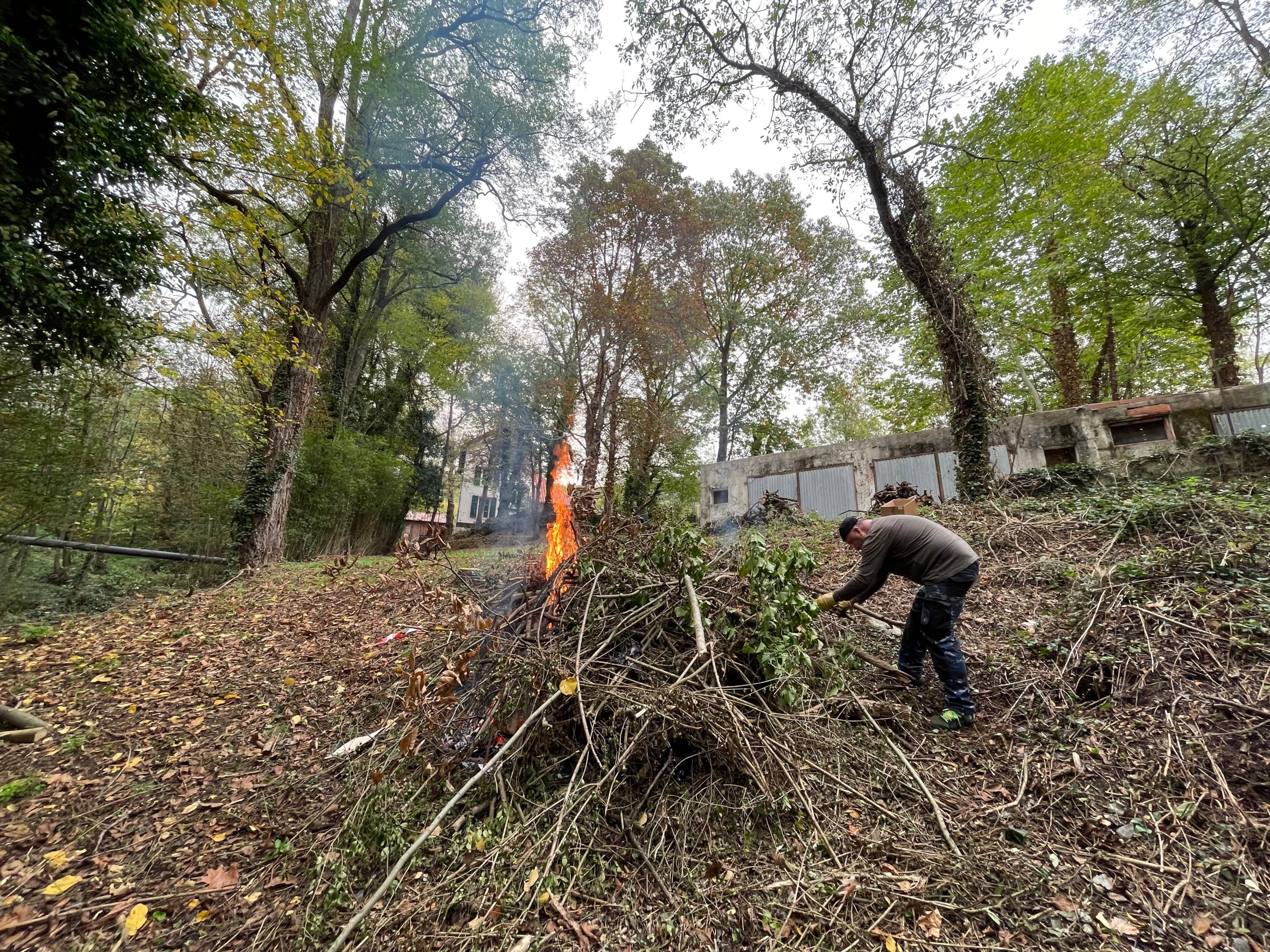 Uno de los voluntarios quema los restos de la poda del jardín en la casa Macià/Quico Sallés