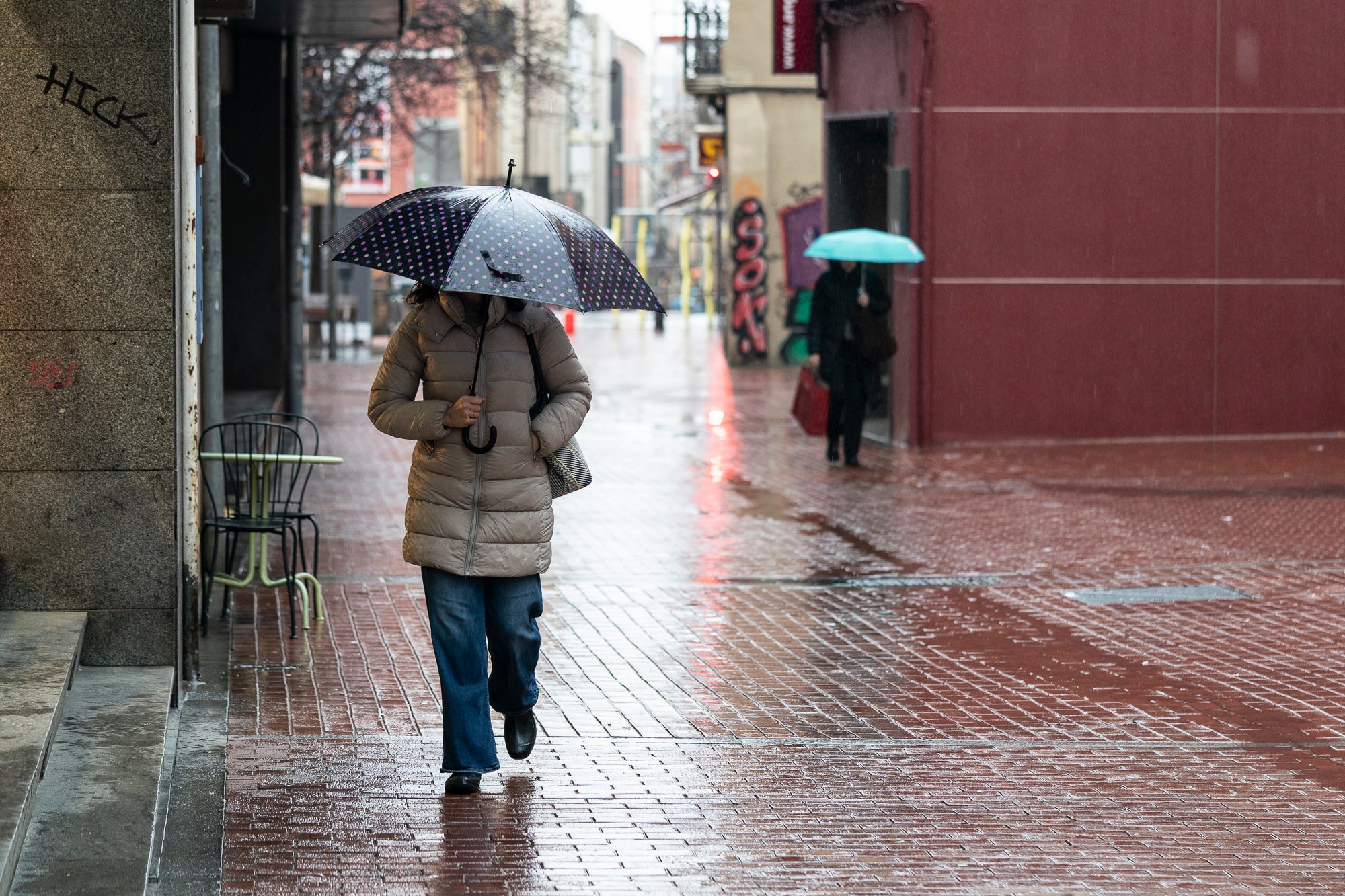 Una persona camina pel carrer sota la pluja / Mireia Comas
