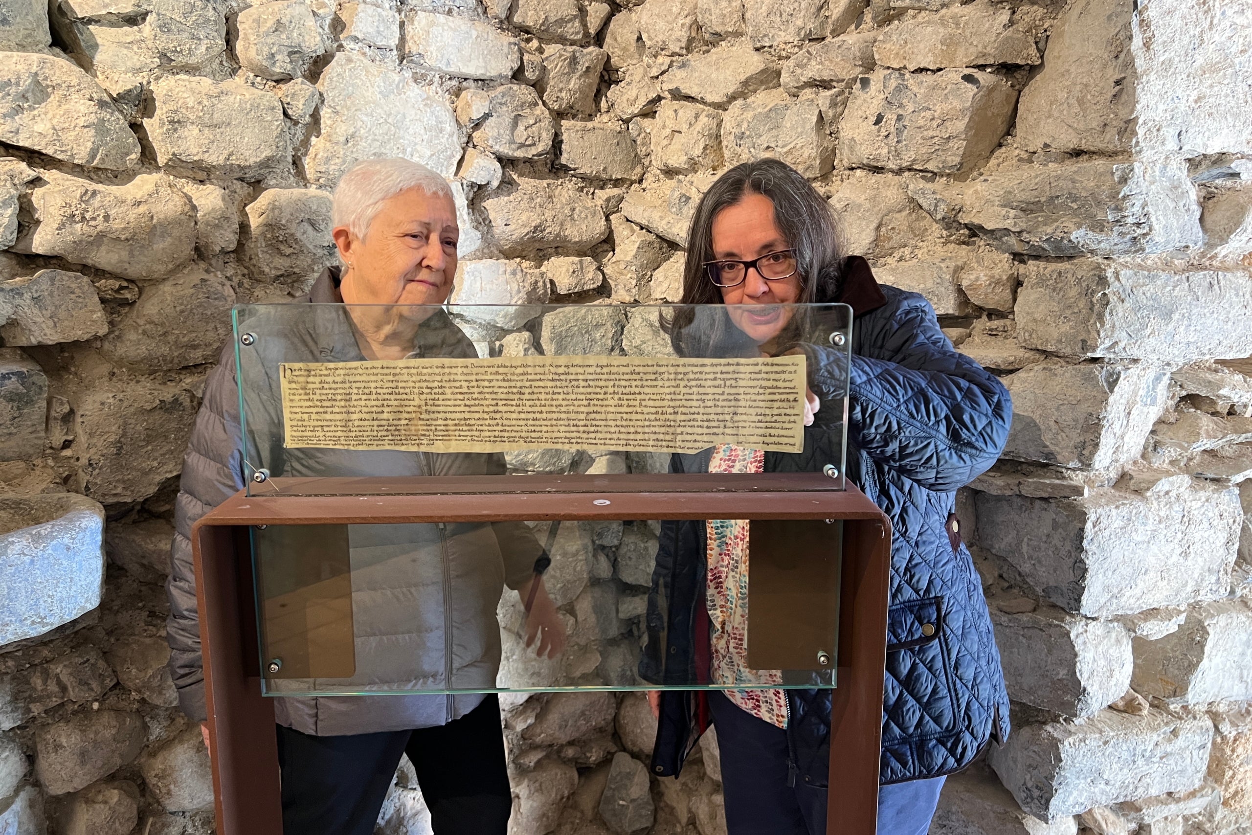 Mercè Casanova i Montserrat Riu, de l’Associació d’Amics de la Vall de Caboet, miren una reproducció dels Greuges de Guitard Isarn, escrit fa 920 anys / ACN