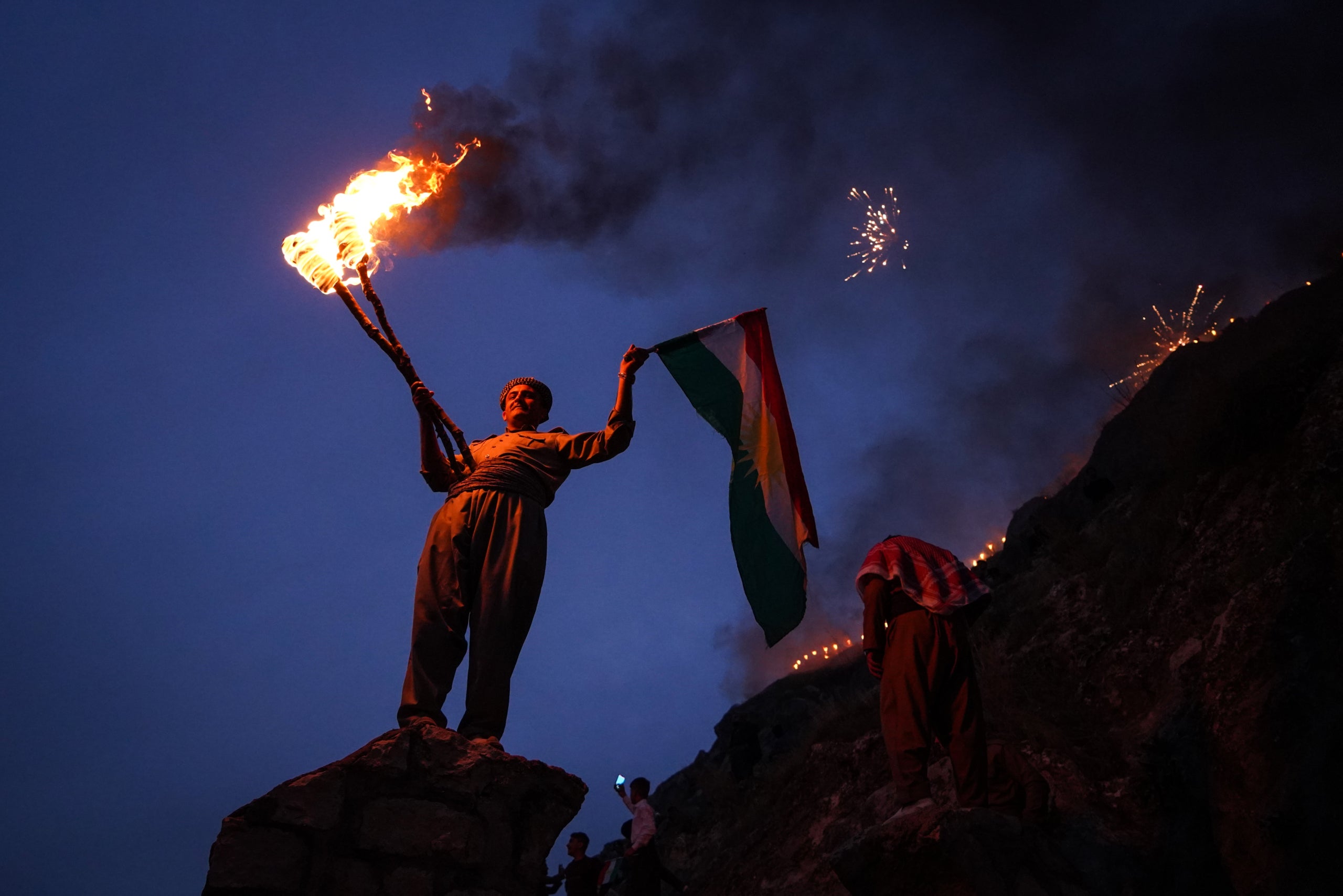 Un home kurd sosté una torxa de foc i una bandera kurda durant les celebracions del Nowruz, l'any nou persa. / Europa Press / Ismael Adnan