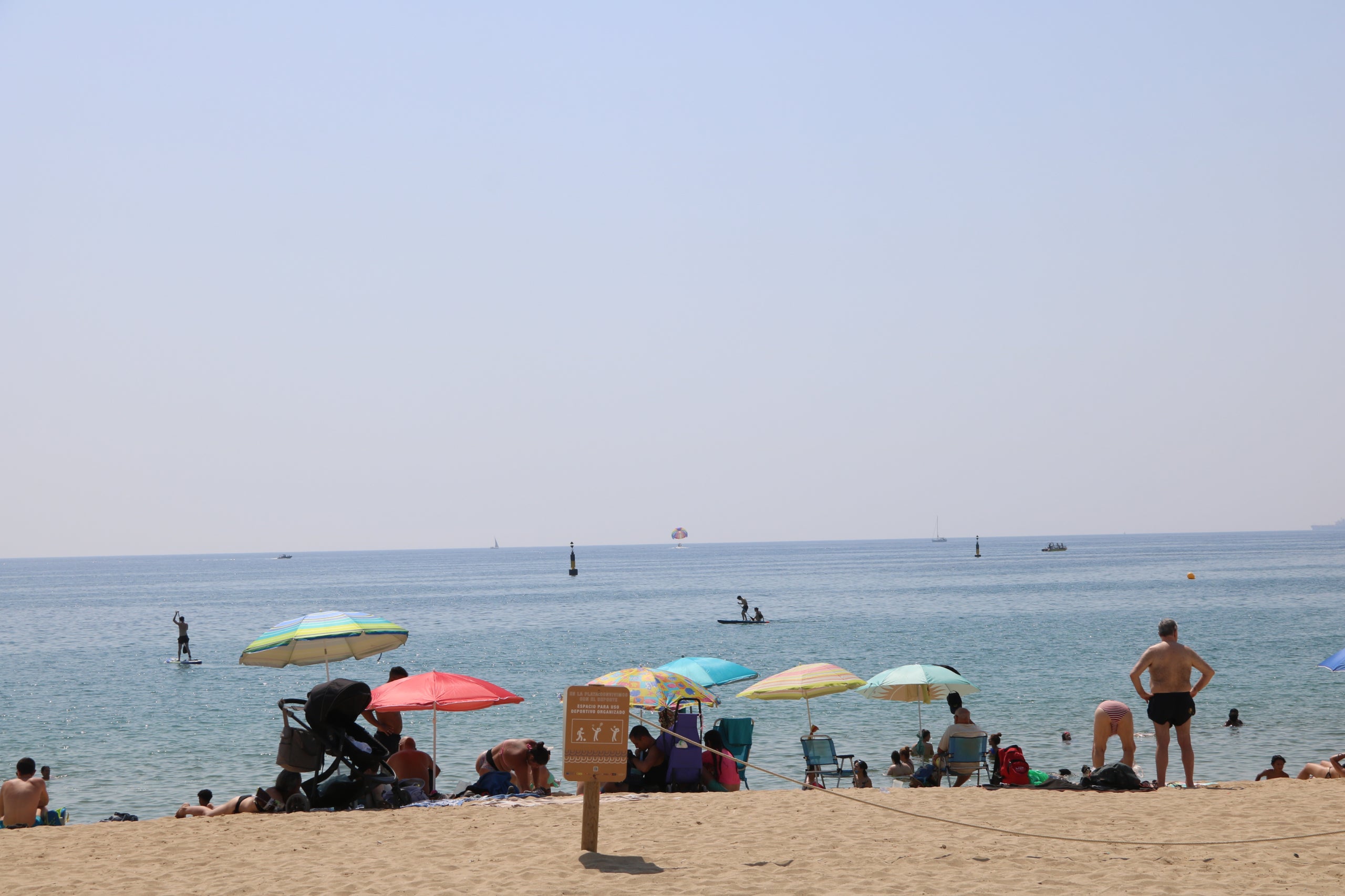 Persones prenent el sol, banyant-se i pràcticant esports aquàtics a la platja del Bogatell | Sara Soteras / Jordi Bataller / Eudald Sanz (ACN)
