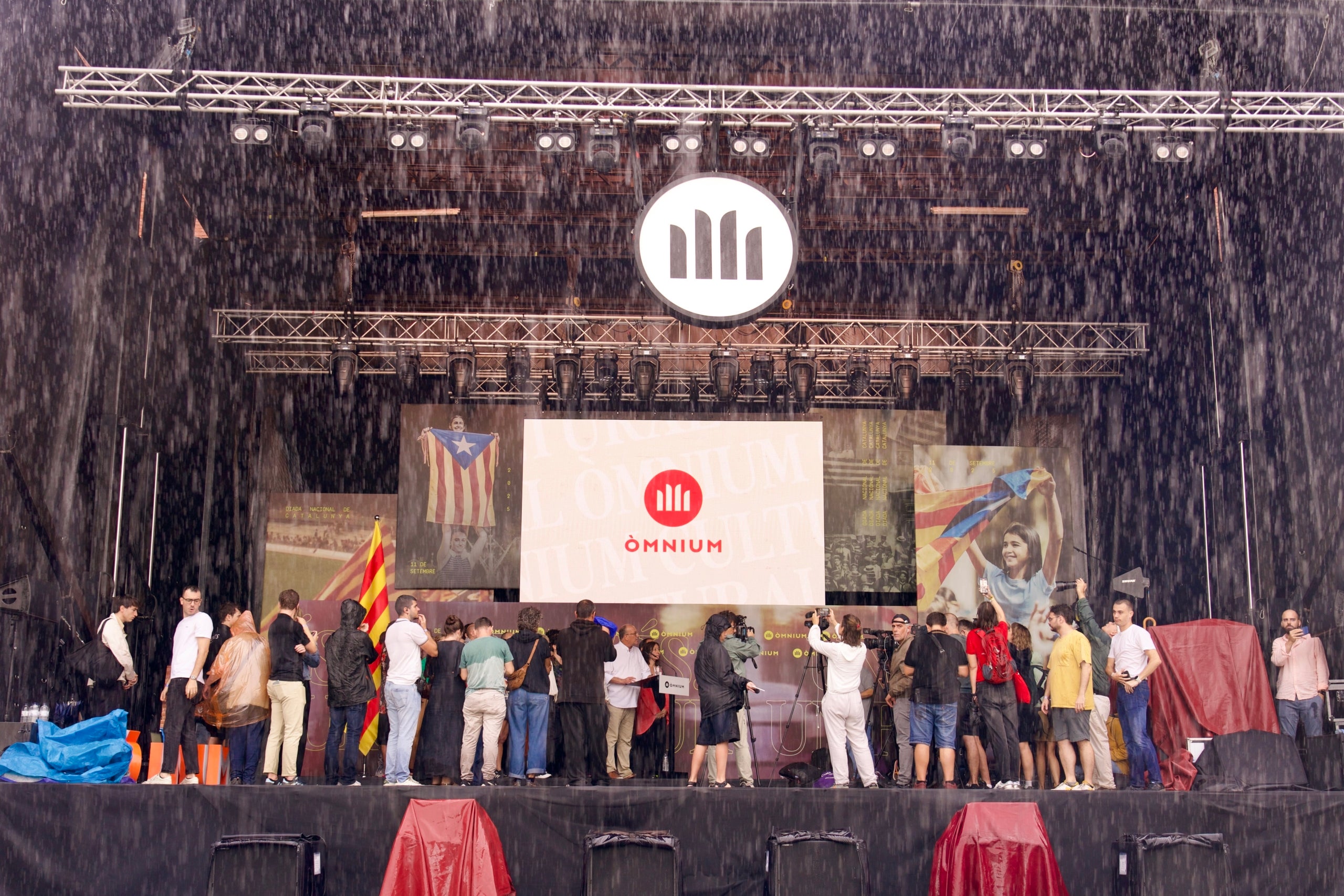El president d'Òmnium Cultural, Xavier Antich, ha fet el seu discurs davant els mitjans de comunicació, tots refugiats a sobre l'escenari per la pluja / Mireia Comas