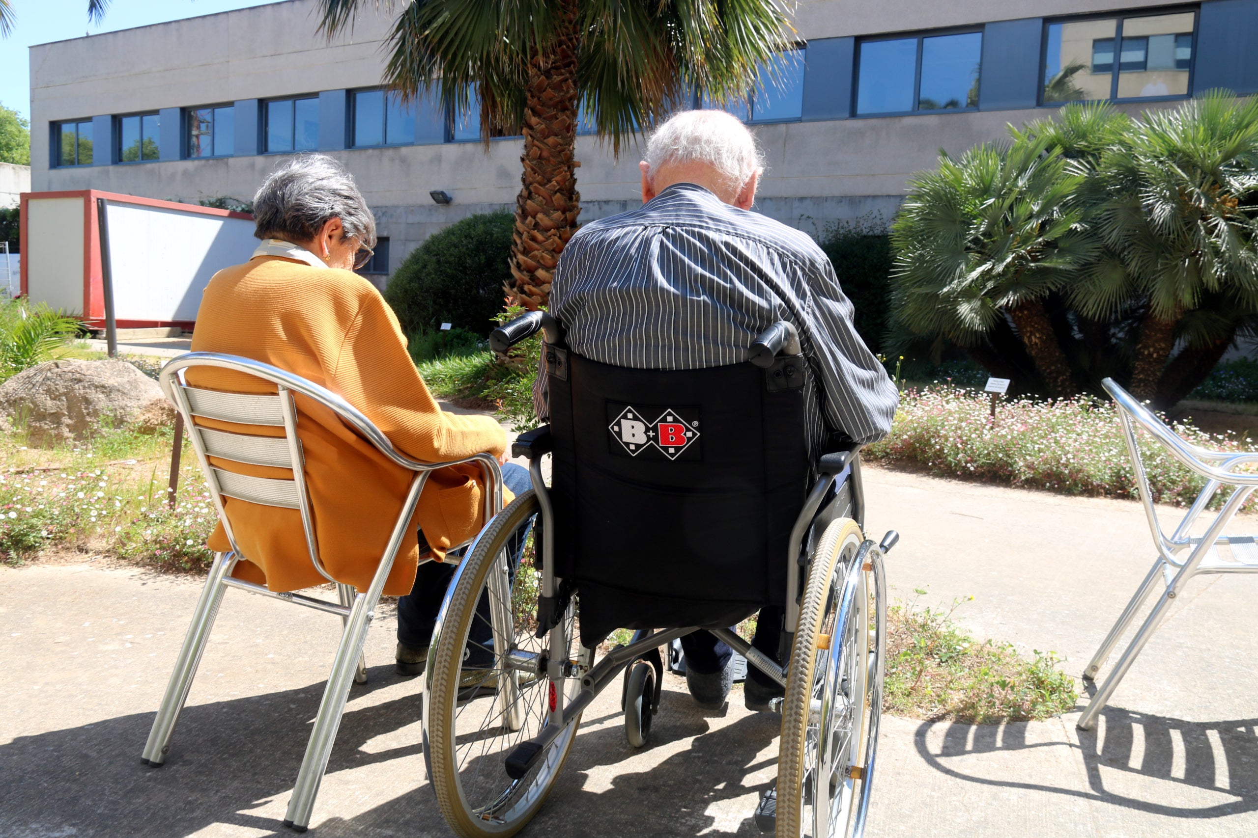 Dos residents prenen el sol al jardí del centre Palamós Gent Gran | Aleix Freixas / Xavier Pi (ACN)