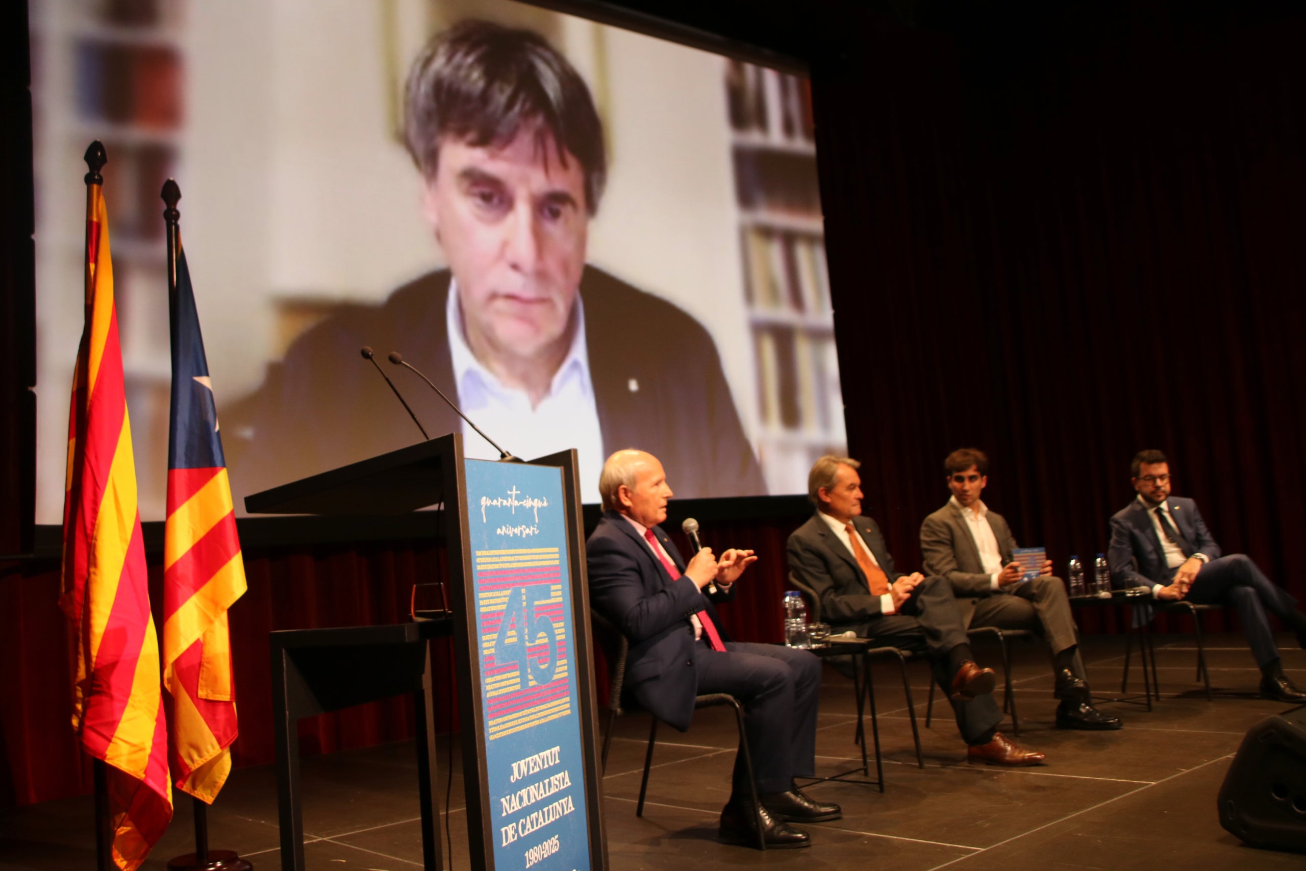 Els expresidents José Montilla, Artur Mas, Carles Puigdemont (a la pantalla) i Pere Aragonès, en l'acte pels 45 anys de la JNC / ACN