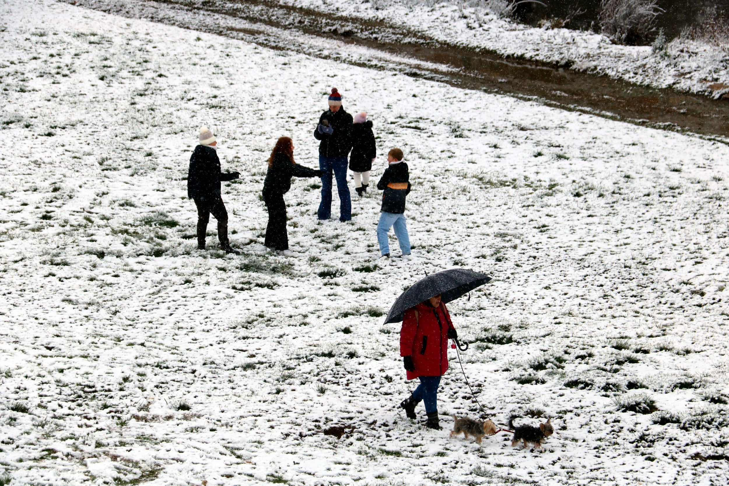 Personas en el canal del río Segre, en Lleida, cubierta de nieve. | Roger Segura (ACN)