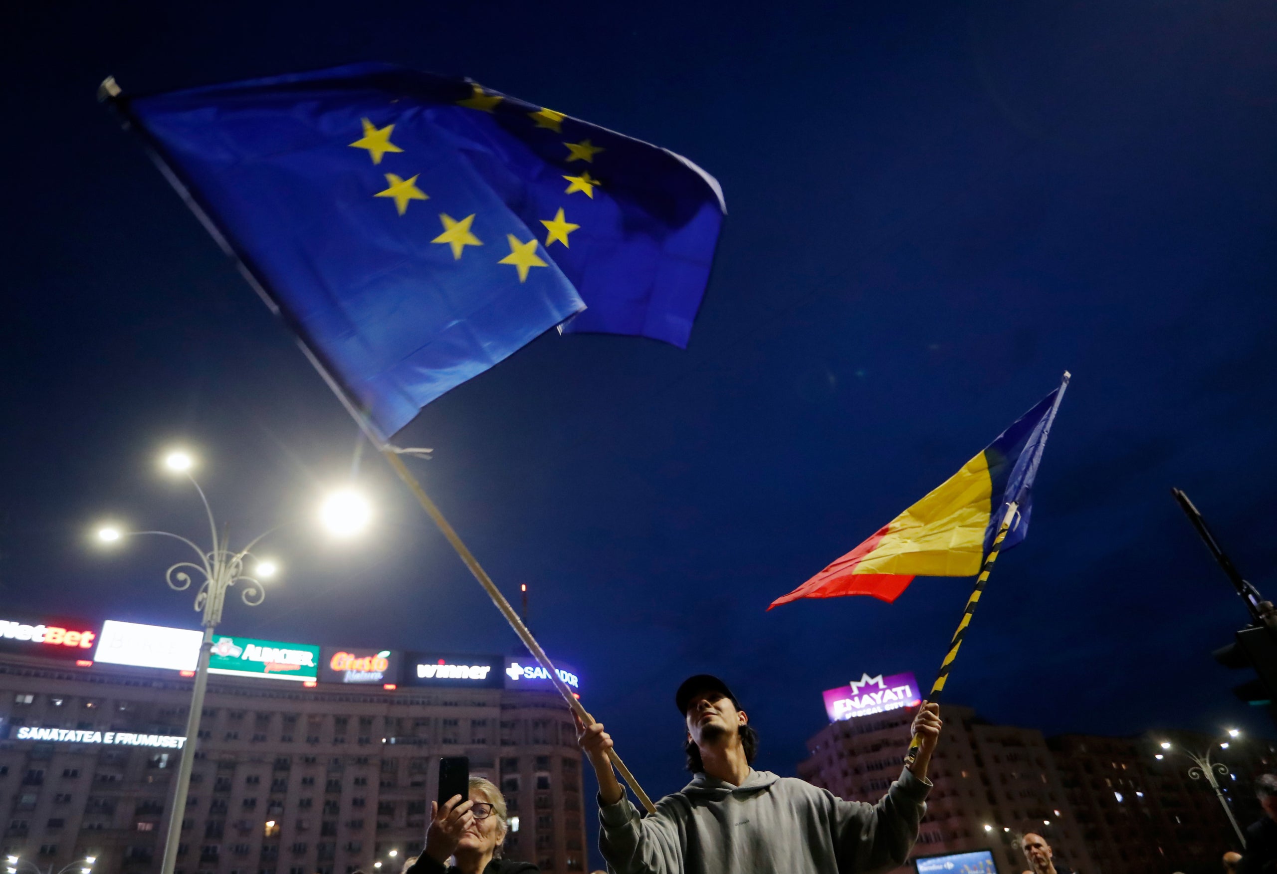  Un home oneja la bandera nacional romanesa i la bandera de la Unió Europea. Europa Press / Contacto / Cristian Cristel