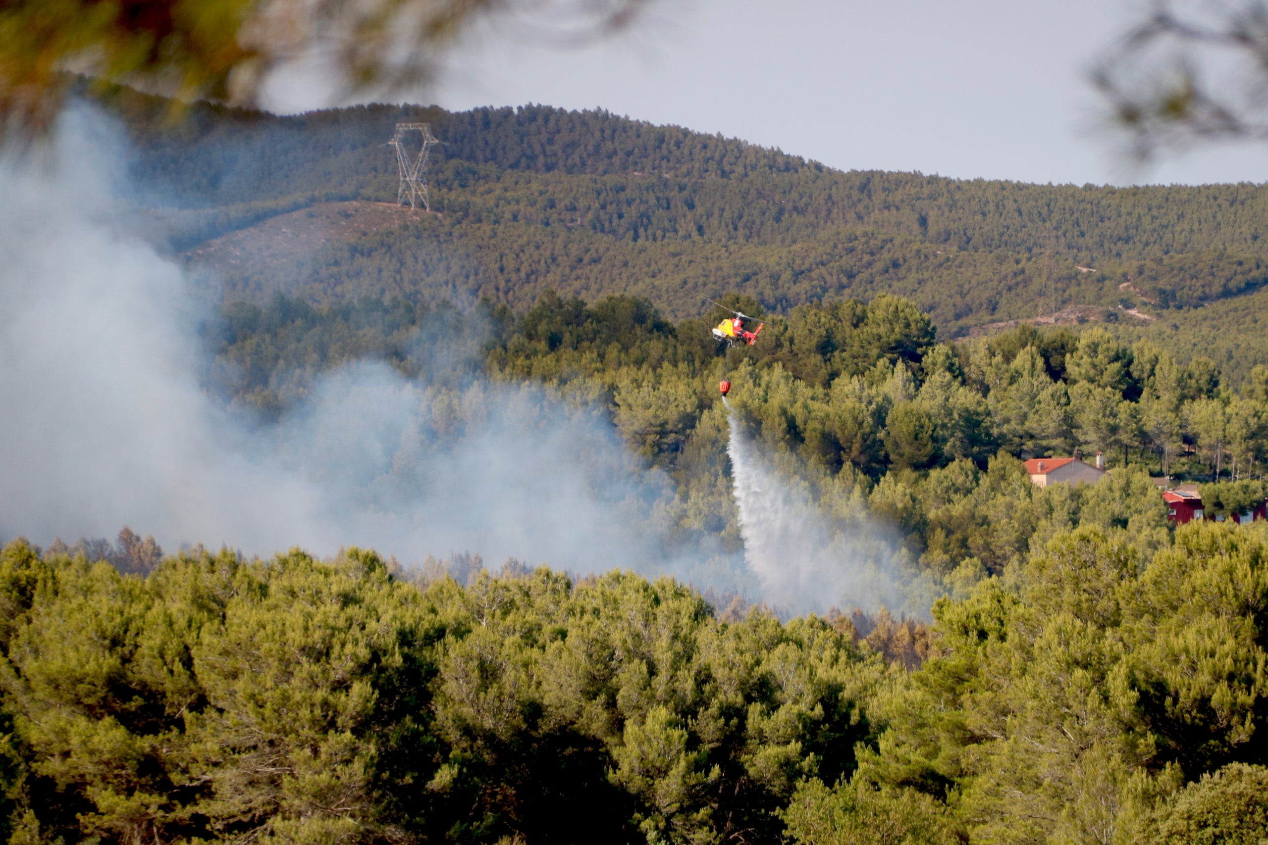 Un helicòpter descarrega aigua sobre l'incendi forestal entre Aiguamúrica i el Pla de Manlleu / ACN
