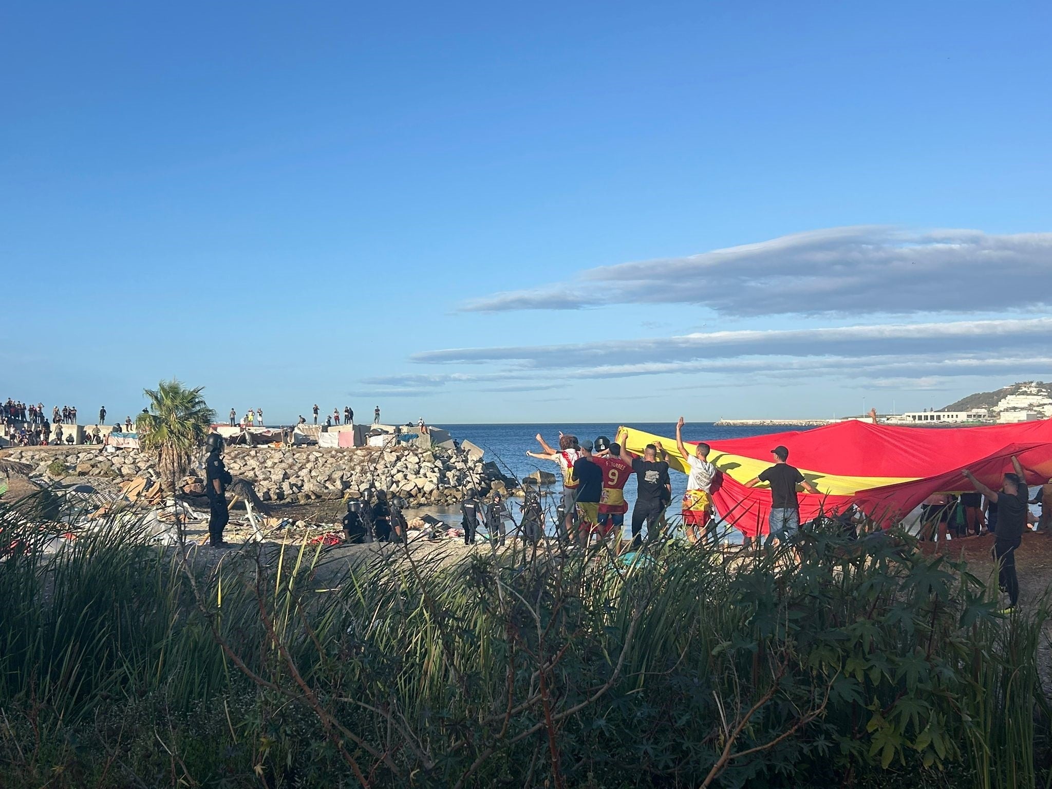 Manifestants amb una bandera gegant d'Espanya a una platja de Ceuta, aquesta tarda / EP
