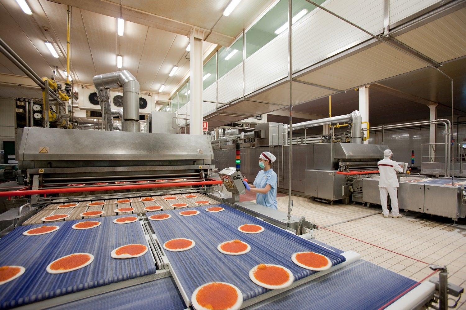 Imatge d'una fàbrica de pizzes de Casa Tarradellas amb treballadores i cadena de producció d'aliments / ACN