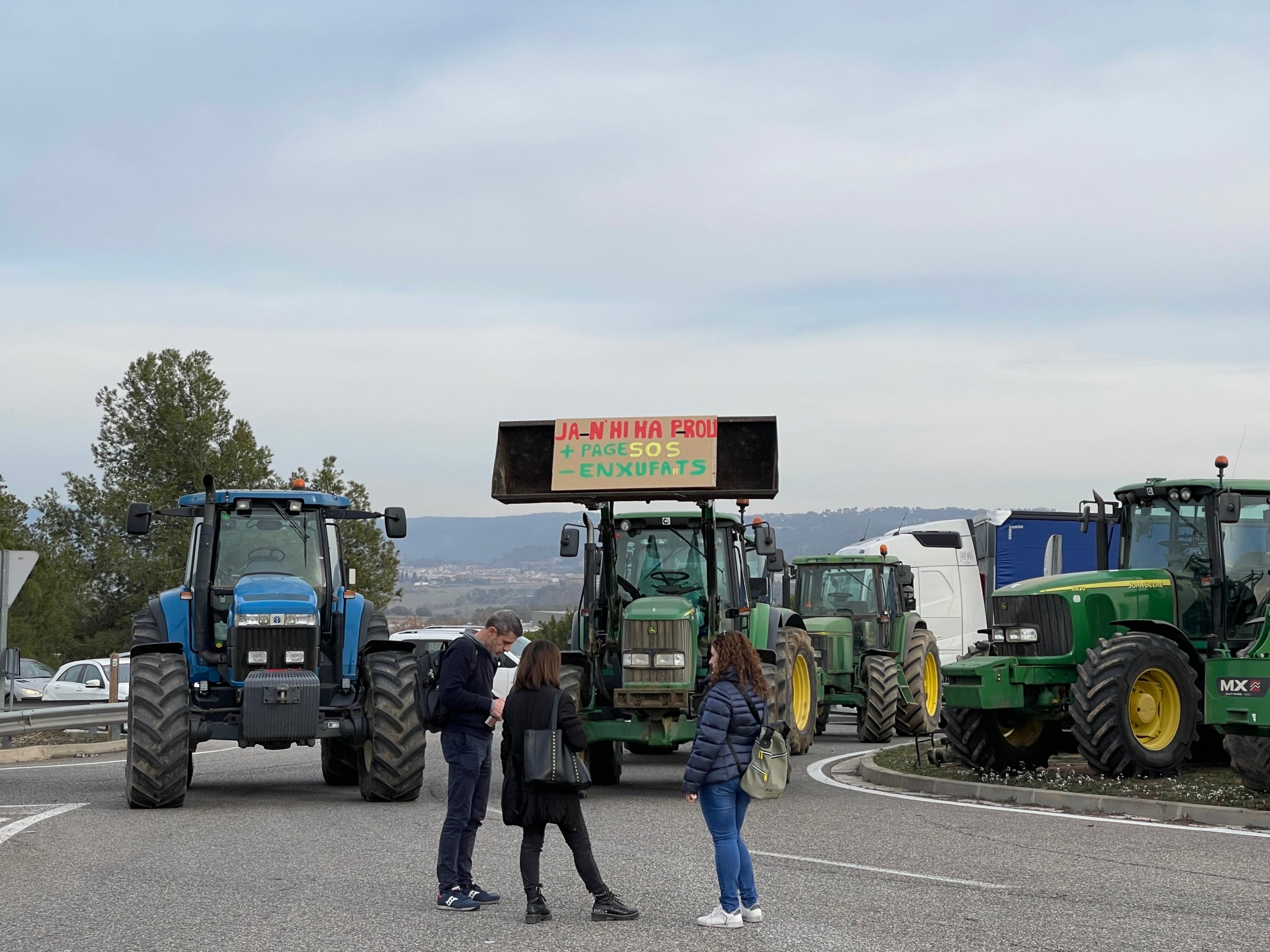 Tres participants a la protesta dels pagesos enraonen davant els tractors aturats amb un dels lemes de la convocatòria/Quico Sallés