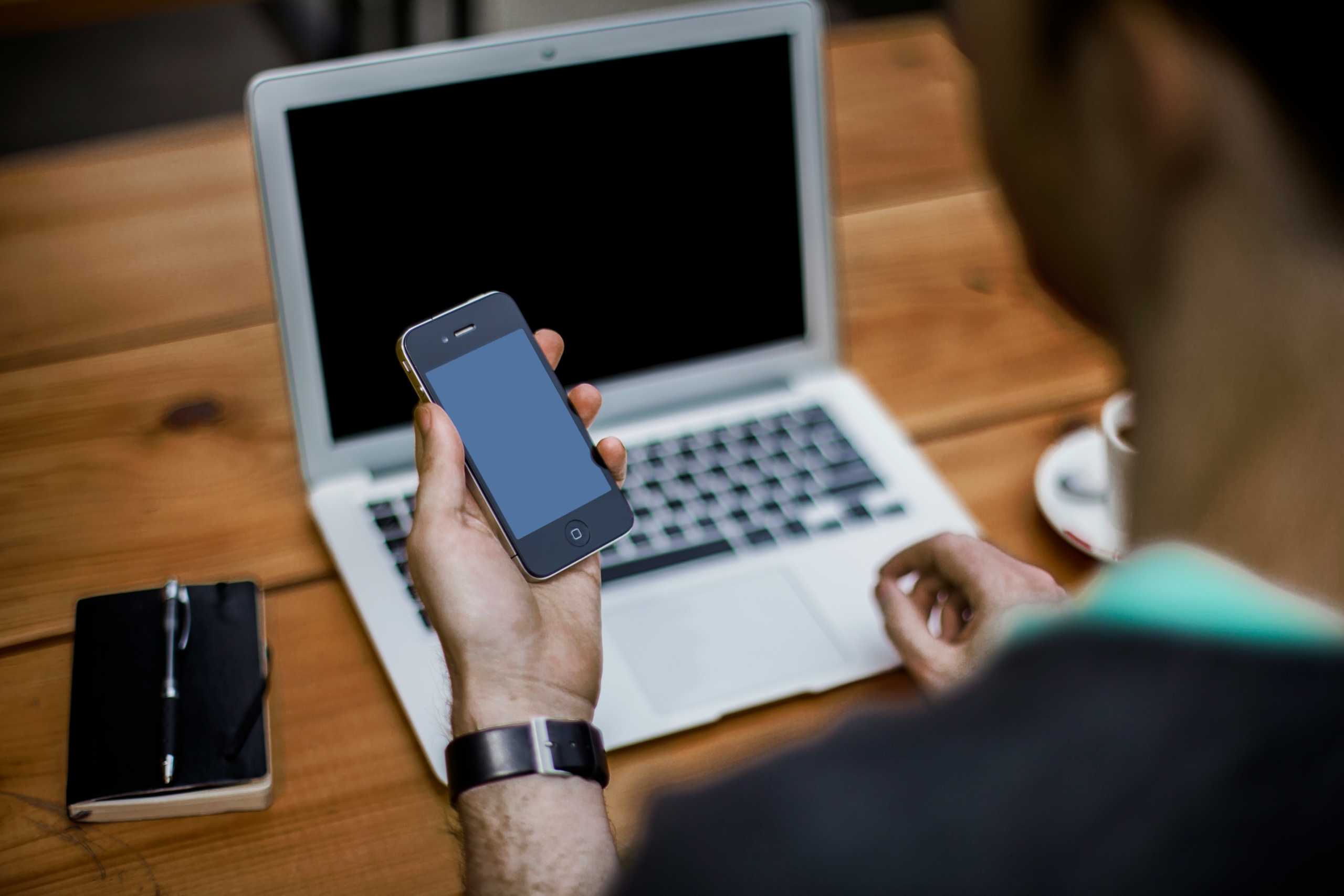 Stock image of a person looking at a cell phone with a computer / Alejandro Escamilla - Unsplash