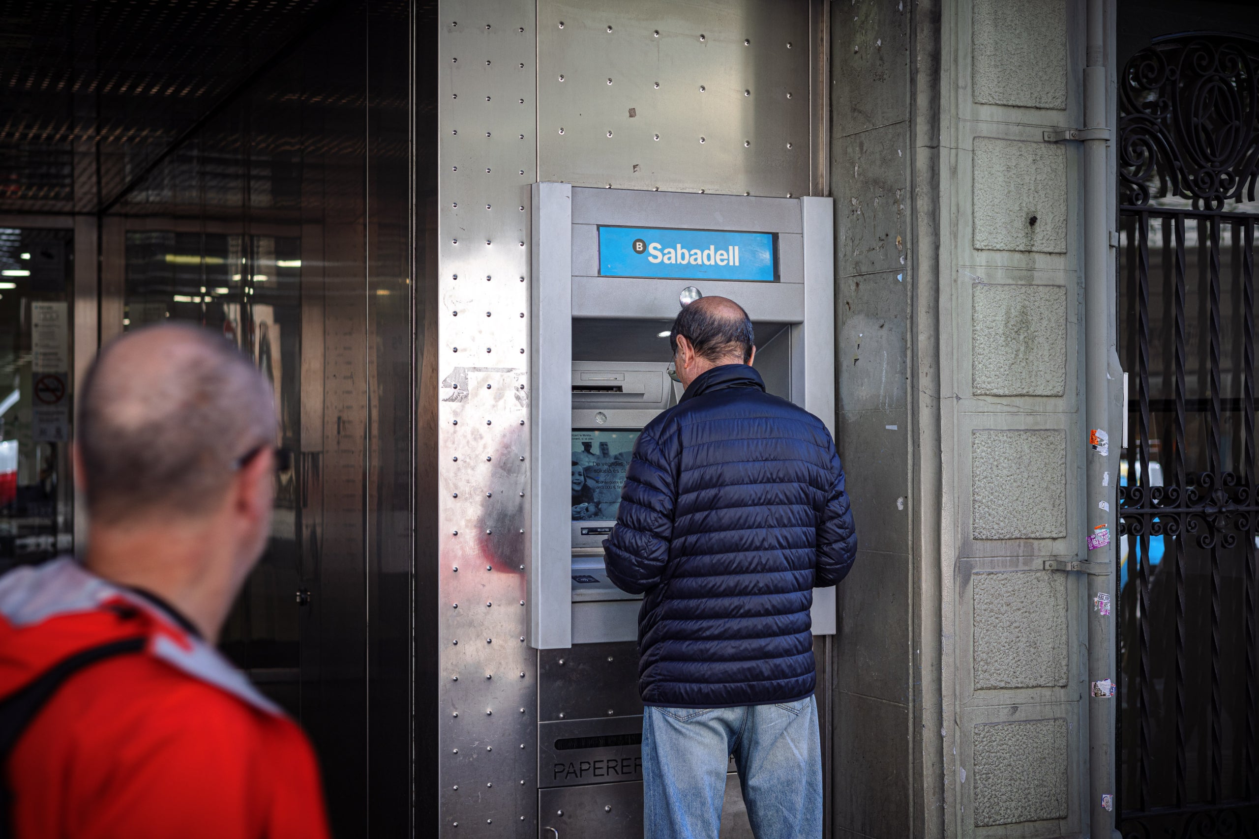 Un home treu diners d'un caixer automàtic del Banc Sabadell / Jordi Borràs